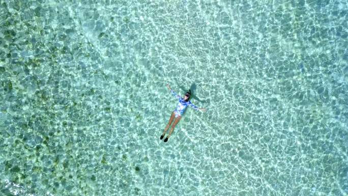 一个女孩漂浮在泻湖上的俯视图