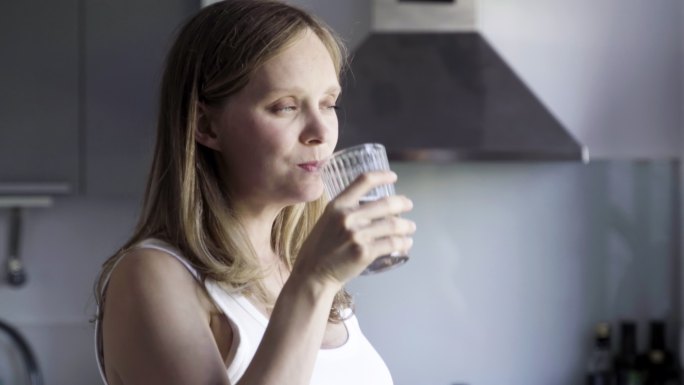 美丽的孕妇用玻璃杯喝水