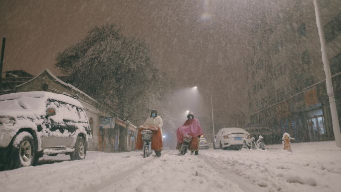 晚上北方小城街道里两个推自行车的人冒雪