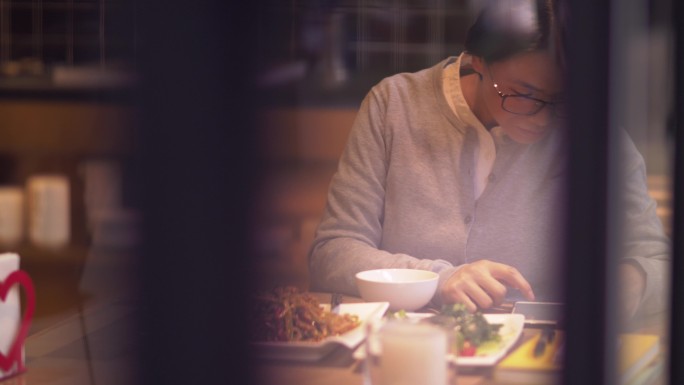 女人在餐厅一边吃饭一边使用手机