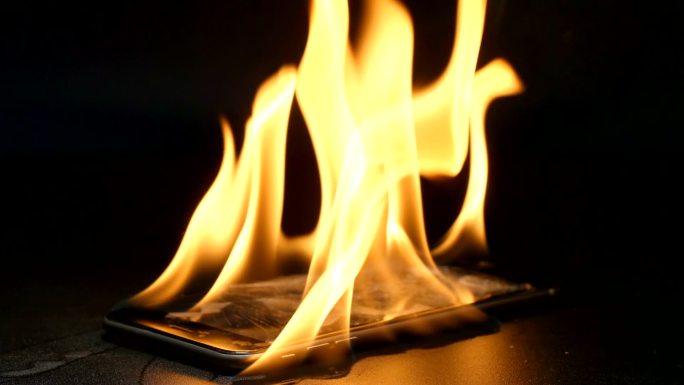 慢动作：破碎的智能手机在桌子上燃烧
