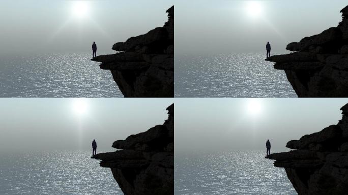 一个男人站在悬崖边看着海浪上的雾的剪影