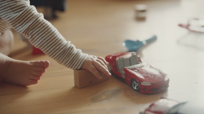 儿童玩汽车模型和地板上的木块
