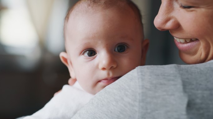 一位年轻妈妈抚摸她抱在怀里的新生儿