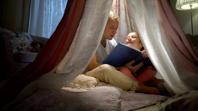 父亲和她的小女儿在家里的帐篷里读书。