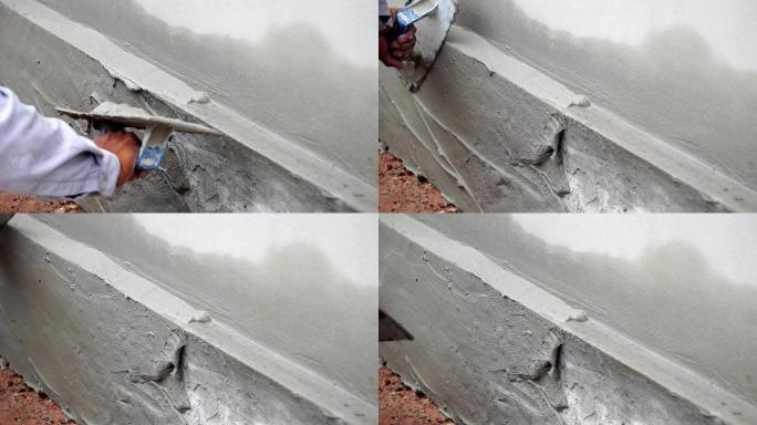 工人使用抹子在施工现场修整湿混凝土墙