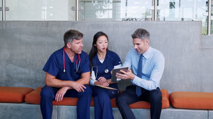 三名医生在医院检查平板电脑上的信息