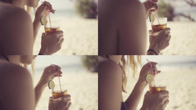 一位美丽的年轻女子在海滩上喝鸡尾酒