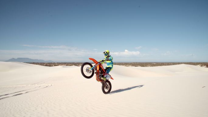 在沙丘上做特技的专业土制摩托车手。