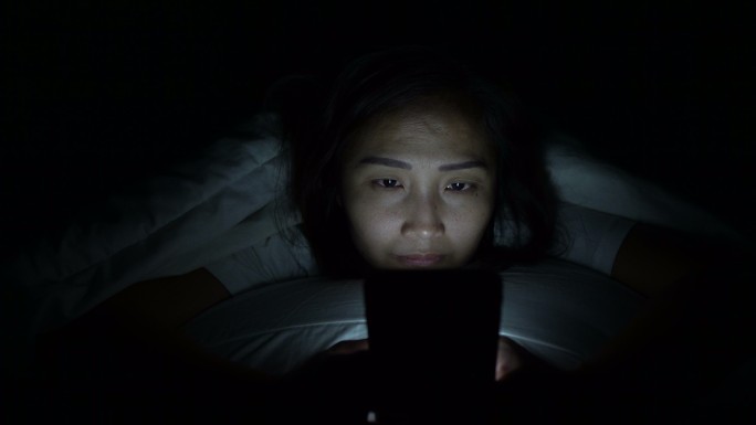 晚上在床上玩智能手机游戏的女人