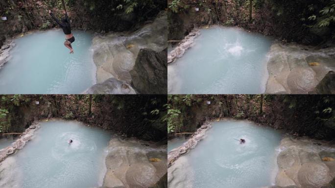 一个穿着泳衣的女人从瀑布的边缘跳到水中。