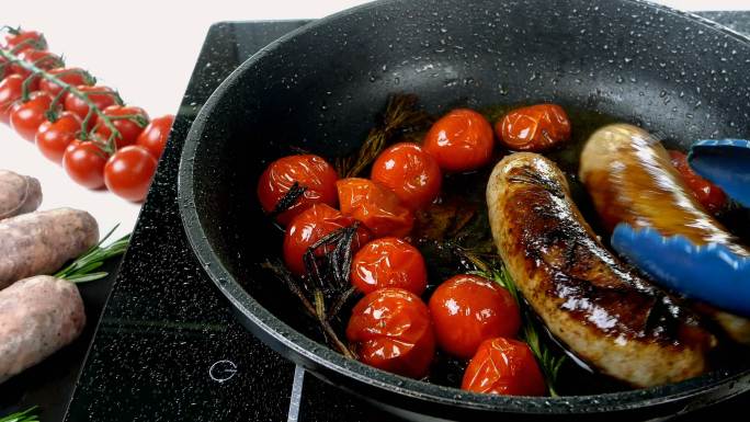 香肠、西红柿和迷迭香在电炉上的煎锅中。