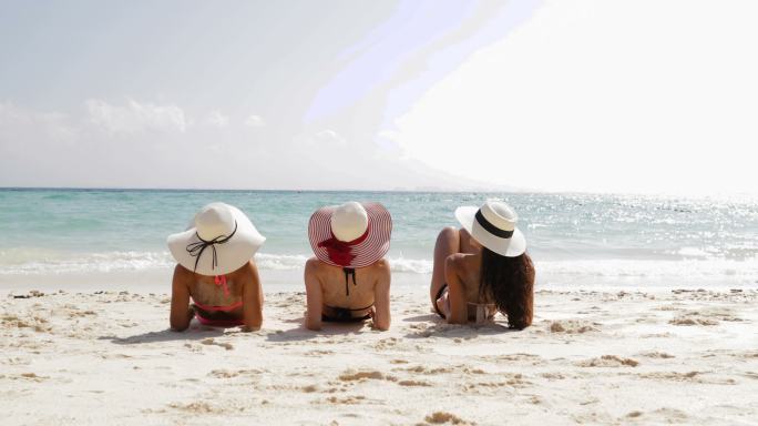 三个女孩仰面仰面躺在沙滩上抬腿，享受日光
