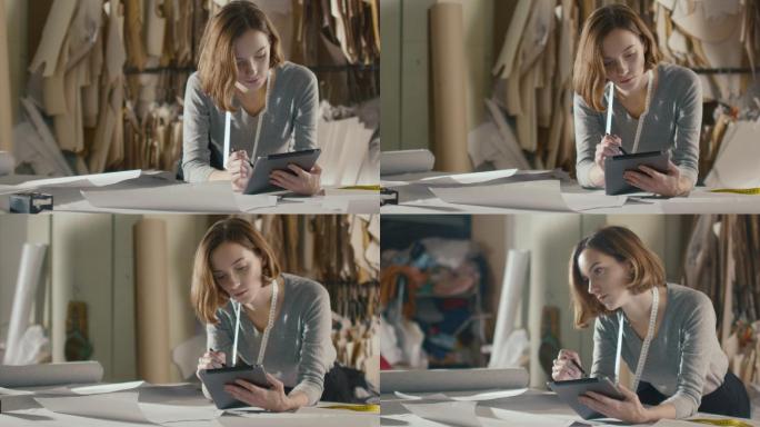 服装设计师靠在工作室的桌子上使用平板电脑