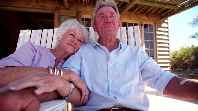 一对退休的老年夫妇在夏天手牵着手坐在户外