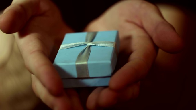 男人拿出一个蓝色盒子的礼物