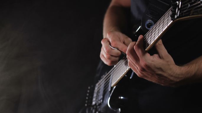 摇滚音乐家在黑色背景上演奏黑色电吉他