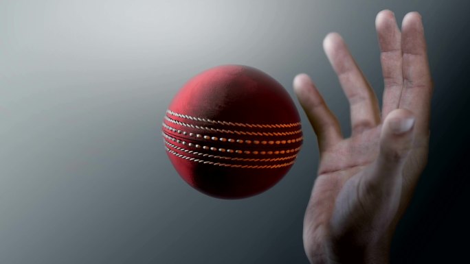 一个红色板球的特写镜头，它被一只脏手抓住