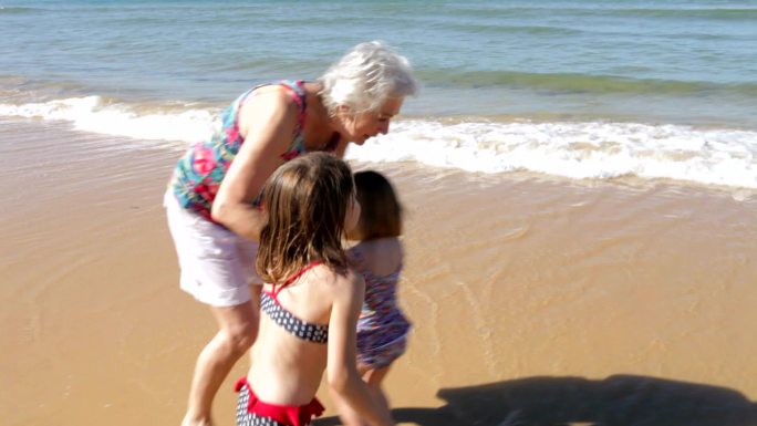 奶奶和孙子孙女在海浪中嬉戏