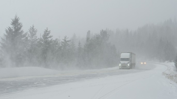 暴风雪肆虐期间，汽车沿着乡村公路行驶。