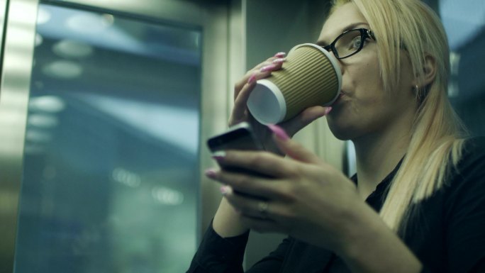 喝咖啡和使用手机的妇女