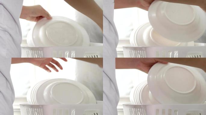 女人把刚洗干净的盘子放在盘子架上