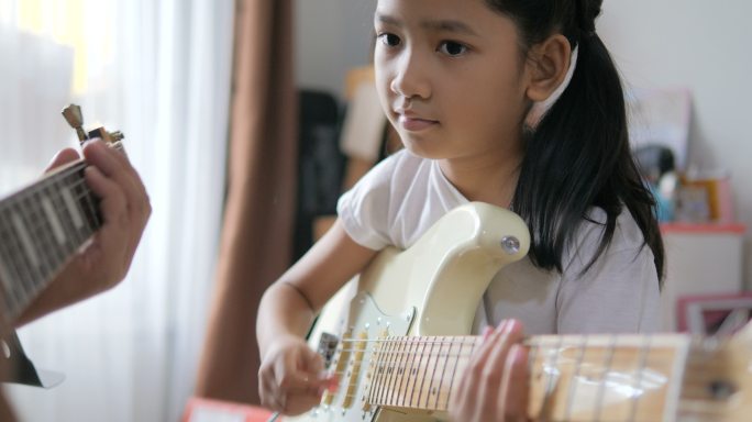 父亲教小女孩弹吉他