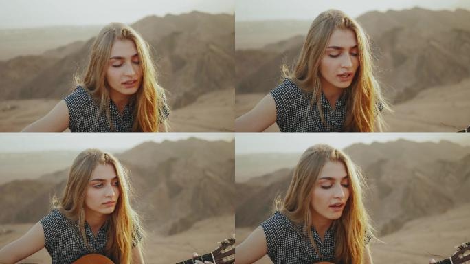 在沙漠山脉背景中弹吉他和唱歌的女人
