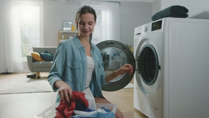 女子把脏衣服装进洗衣机。明亮宽敞的客厅
