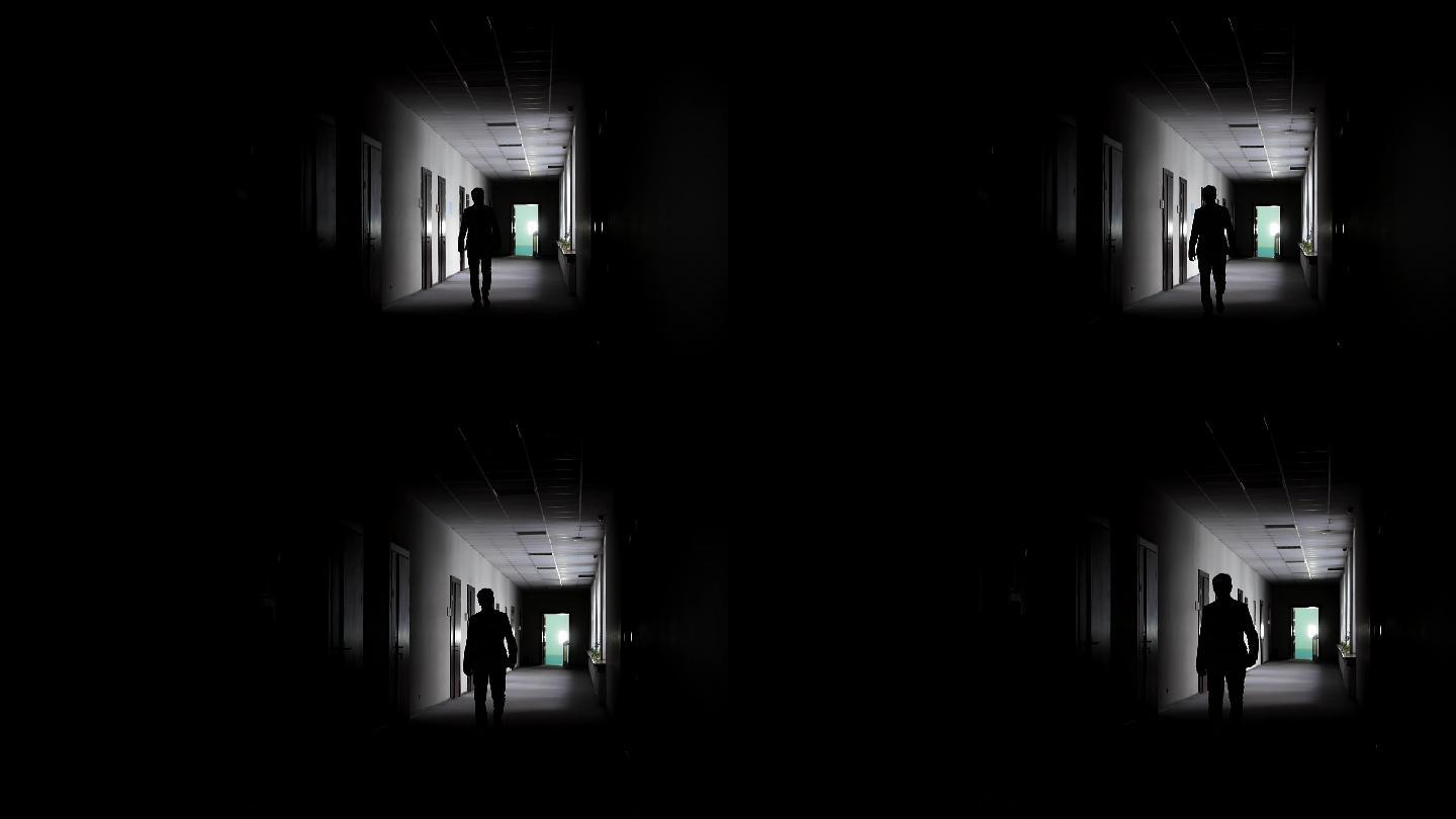 一个男人在背光下走过一条长长的走廊