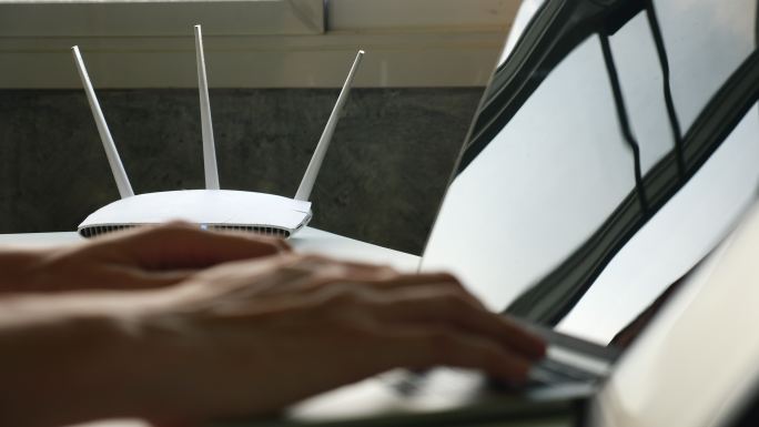 一个无线路由器和一个人在桌上使用笔记本电脑
