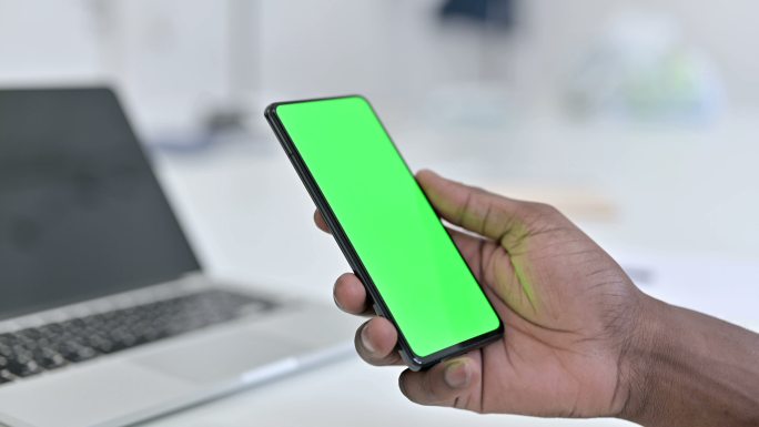 男子手持绿色智能手机屏幕