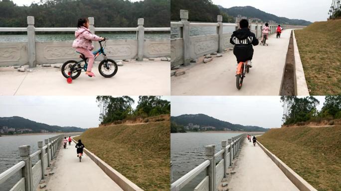 河边小孩子骑车沿江小道单车江畔护栏