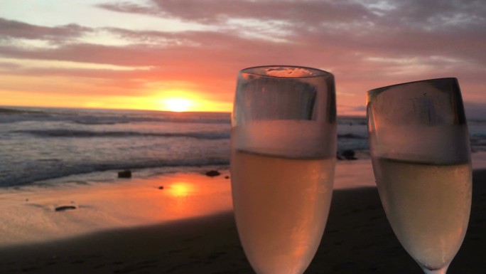 海滩上壮丽的夕阳下的两杯香槟酒