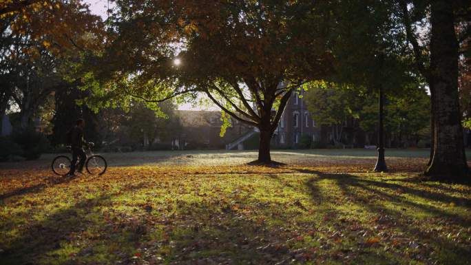 大学生在校园里推着自行车走过