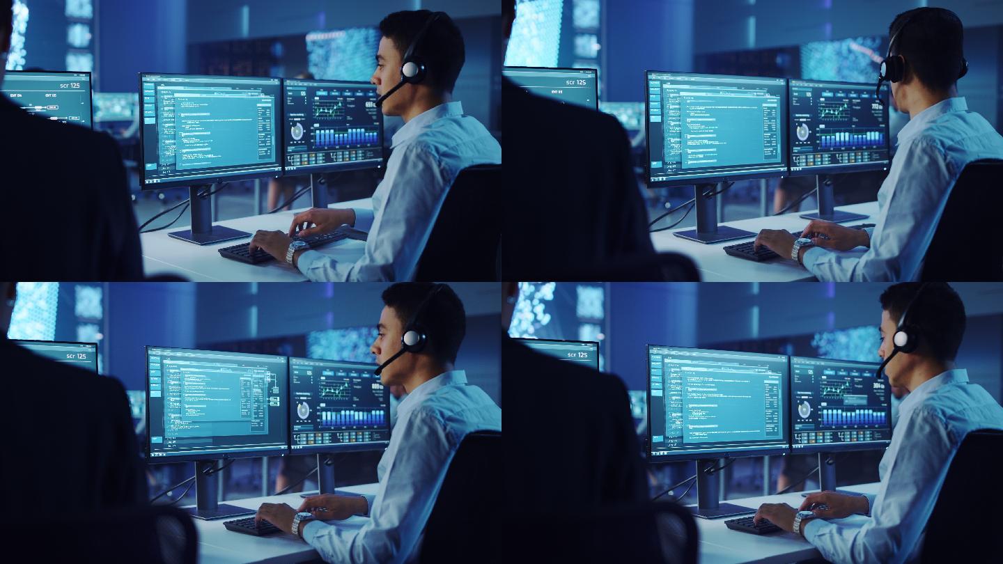 男性工程师在监控室戴着耳机在电脑上工作。