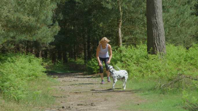 一个女人和狗狗在森林里奔跑