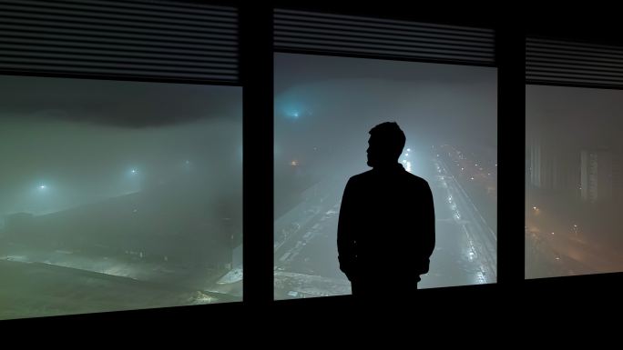 这个男人站在窗户附近眺望雨中城市