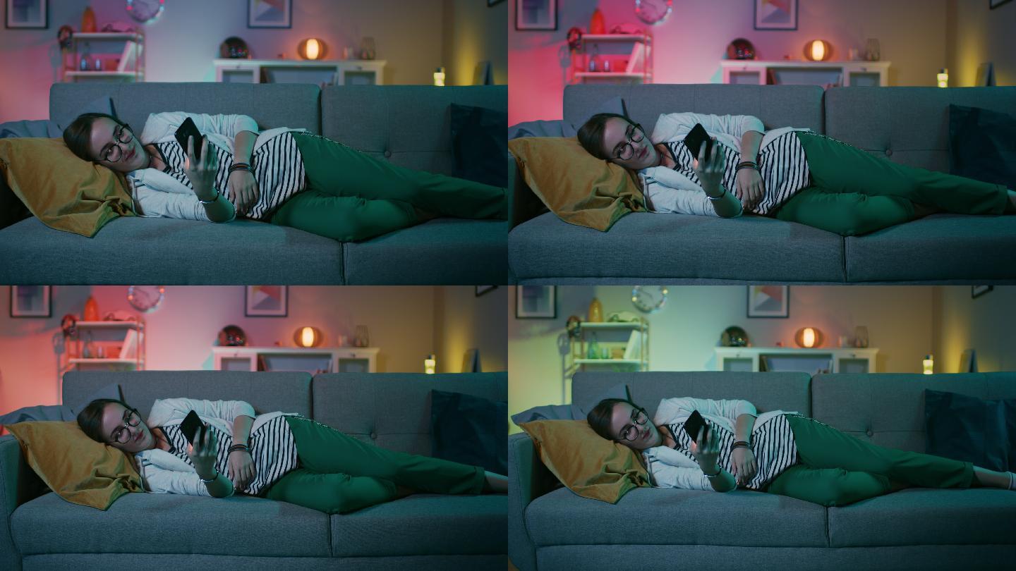 年轻女孩躺在沙发上，用她的智能手机。