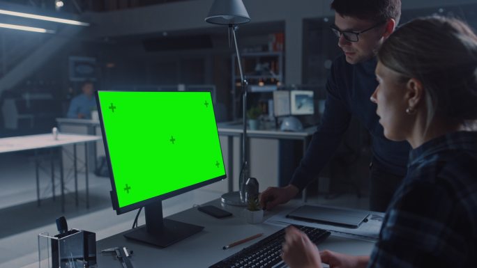工程师在台式电脑上工作，屏幕显示绿色屏幕