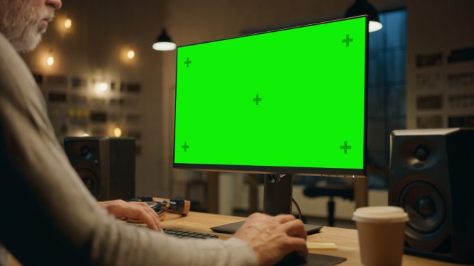 设计师使用带有绿色模拟屏幕的台式电脑。