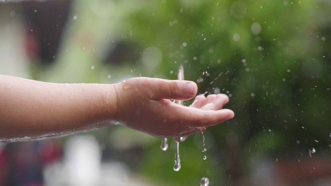 小孩子玩水的镜头雨滴掉落小孩玩水手接雨水