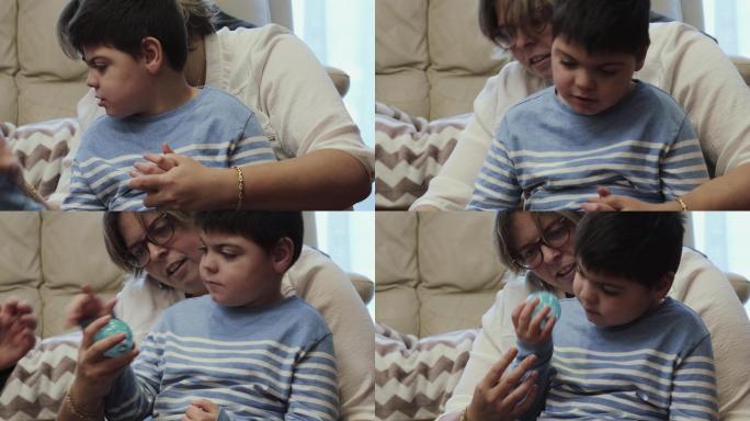 残疾儿童坐在母亲的膝上，玩着橡胶球。