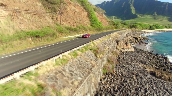 红色敞篷车沿火山海岸上方的海岸公路行驶