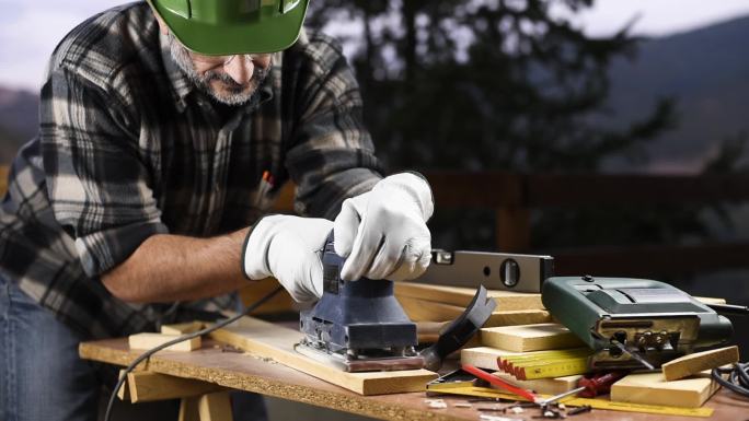 木匠用电动砂光机打磨木桌