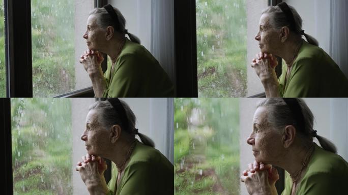 老妇人向窗外望去老人眺望远望窗户窗台雨中
