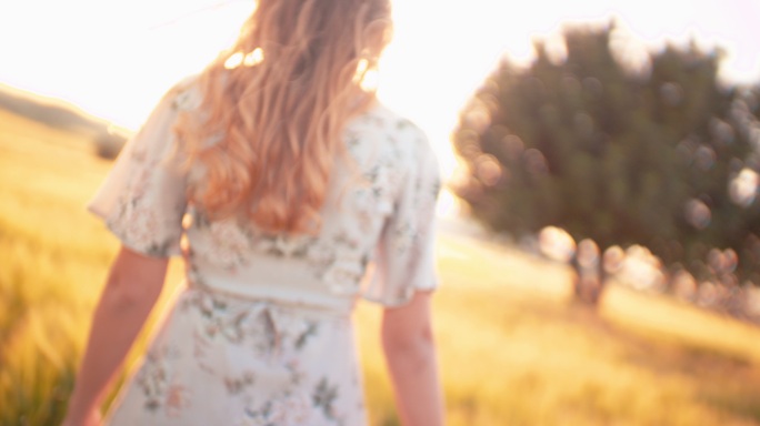 金色头发的年轻女子漫步在金色的田野