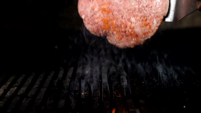 美味的汉堡肉饼在灼热的烤架上翻转