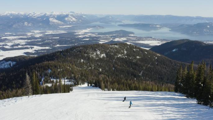 无人驾驶飞机飞过滑雪坡上的两个人在滑雪