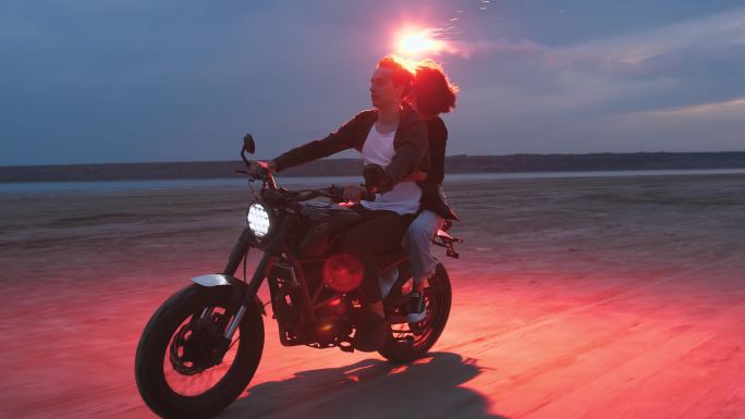 骑摩托车的情侣情侣在海边骑摩托浪漫玩烟花